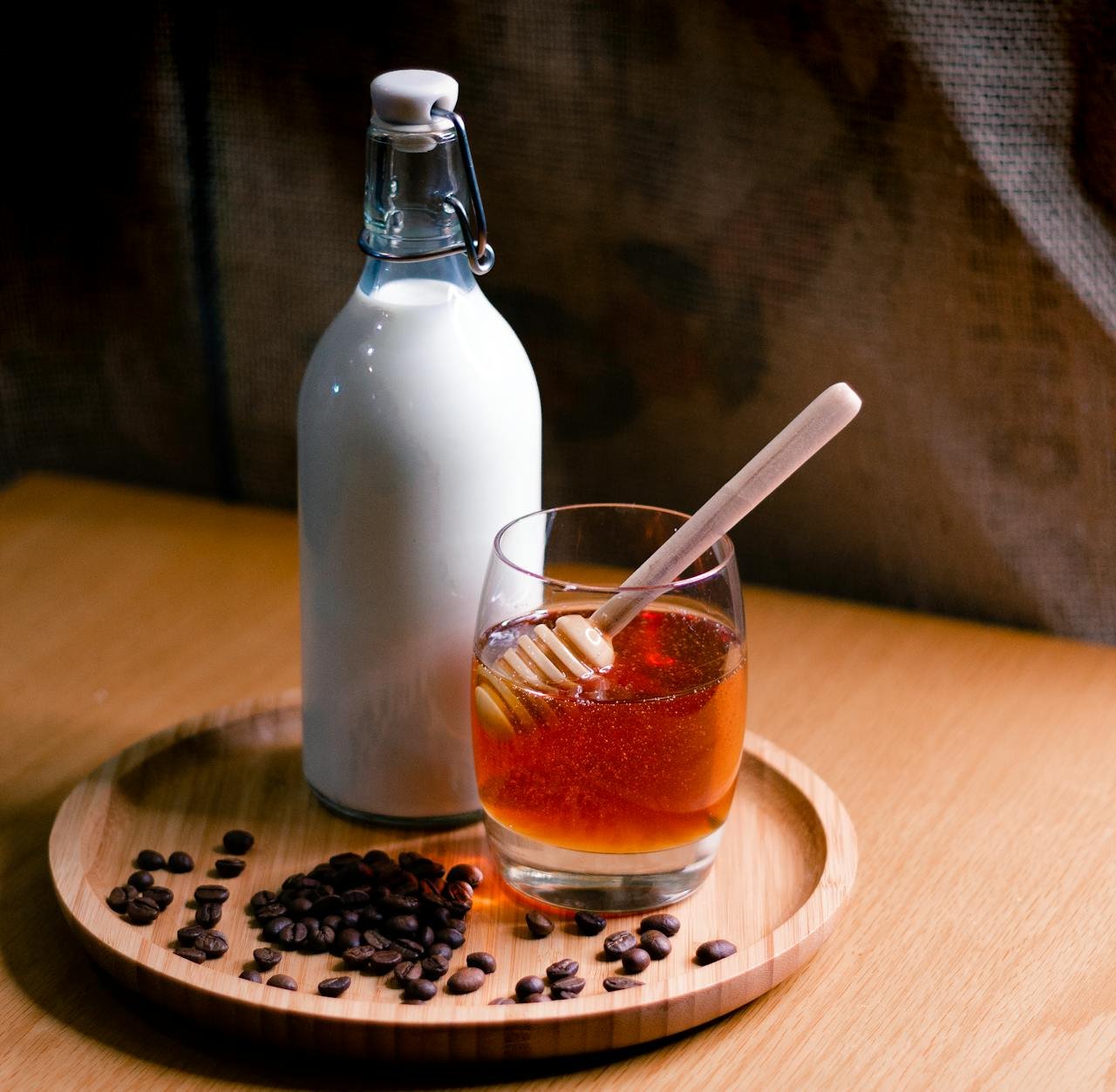 services-01 Elegant setup featuring a milk bottle and honey glass on a wooden tray with coffee beans.